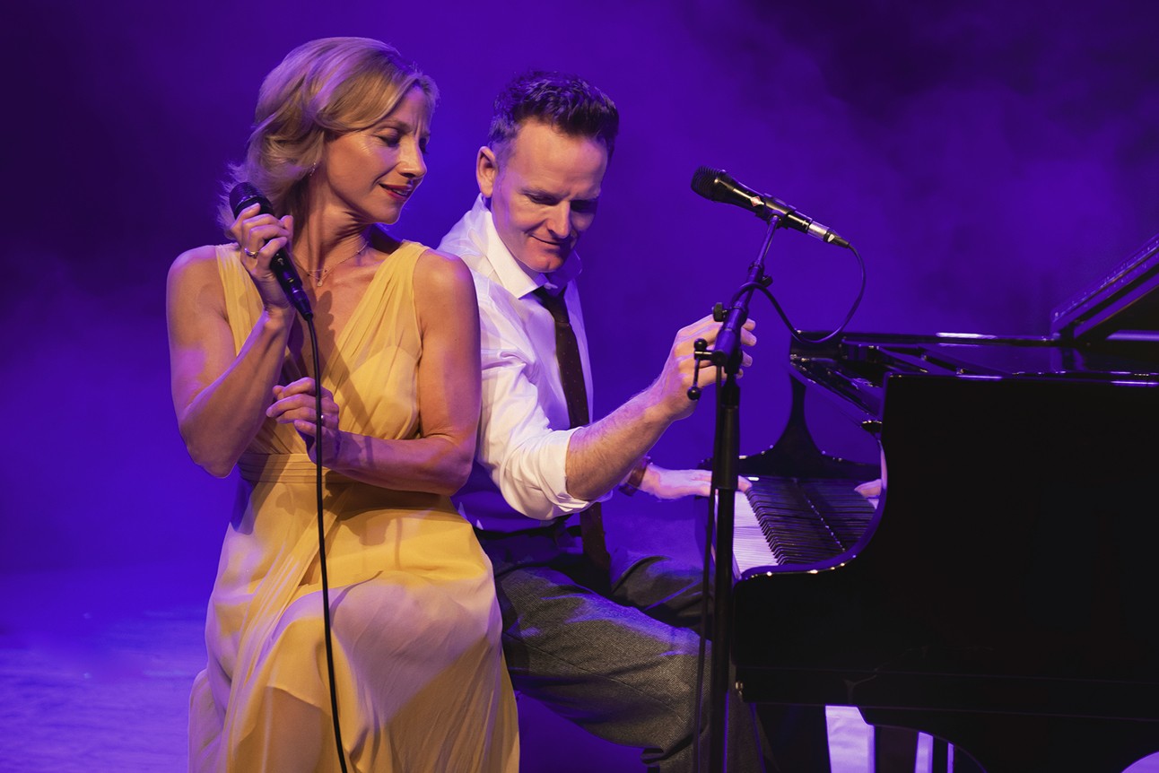 Liza Pulman and Joe Stilgoe performing on stage with a vibrant Hollywood-themed backdrop.