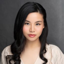 Eunice De Castro smiling, wearing a formal outfit, against a backdrop featuring Asian cultural elements.