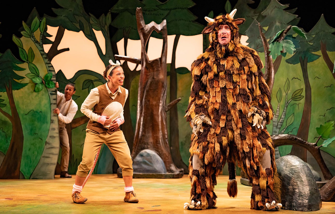 Actors in detailed animal costumes perform on stage with painted forest backdrop during The Gruffalo production.