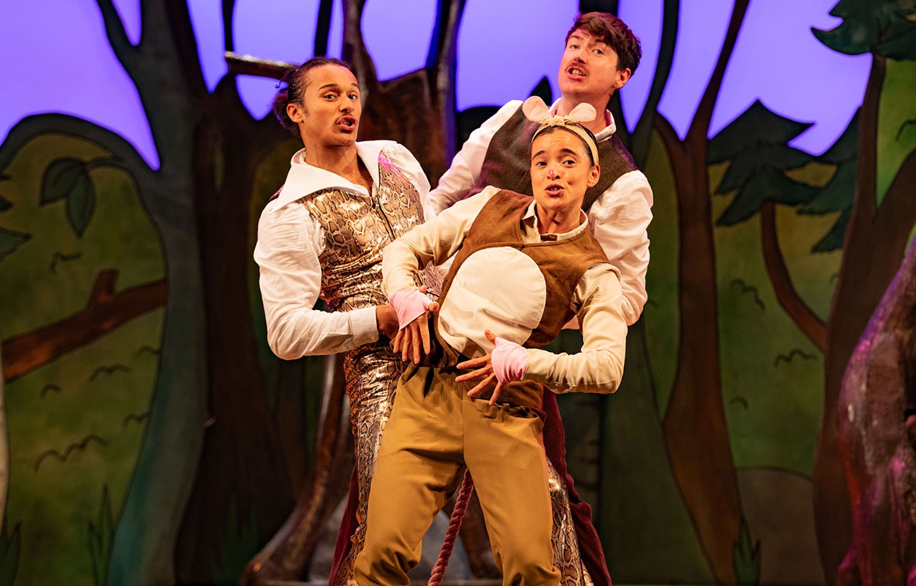 Three actors in The Gruffalo costumes perform animatedly on stage with a dark forest backdrop.