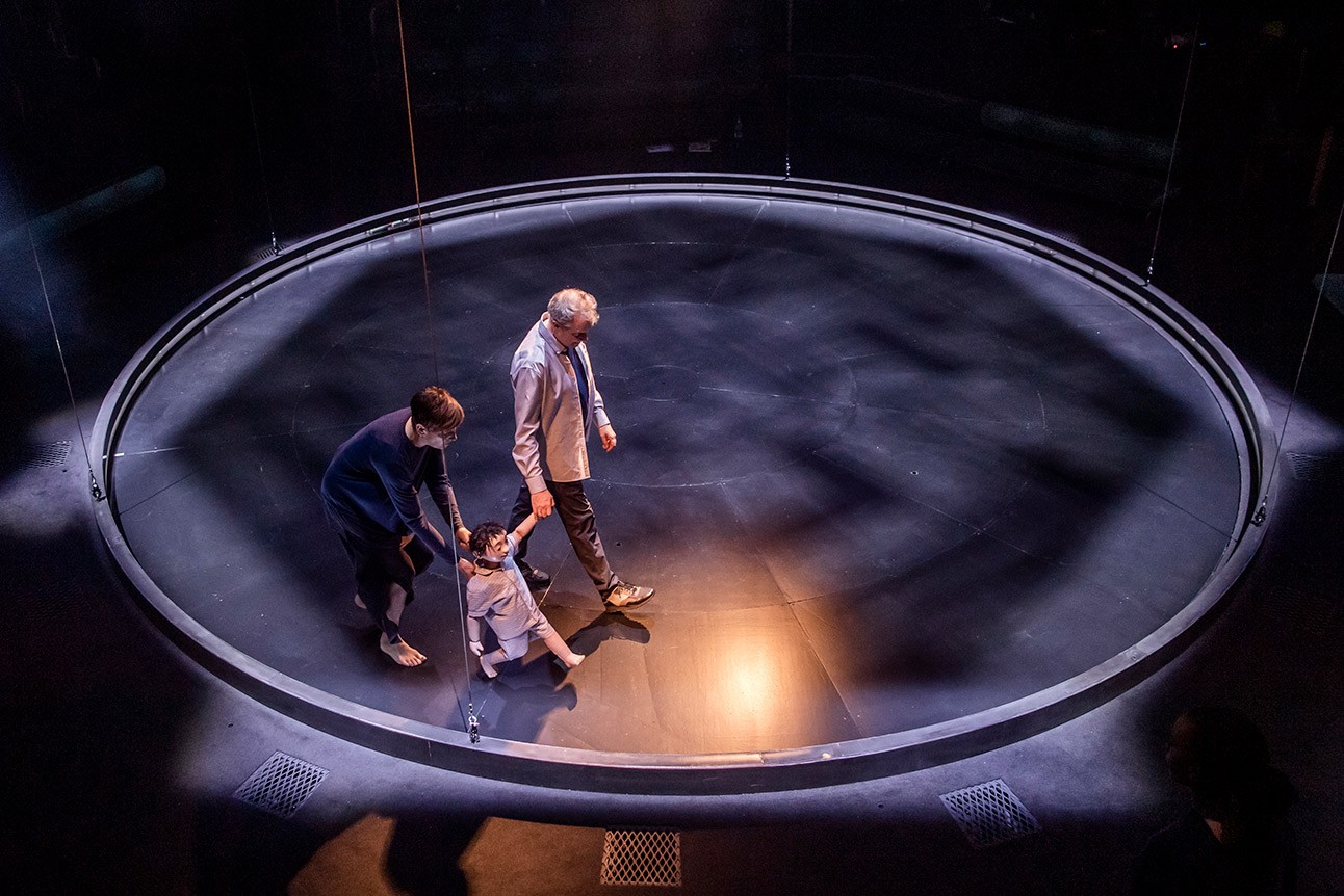 Phelim McDermott and Sara Wright perform on a circular stage with dramatic lighting effects.